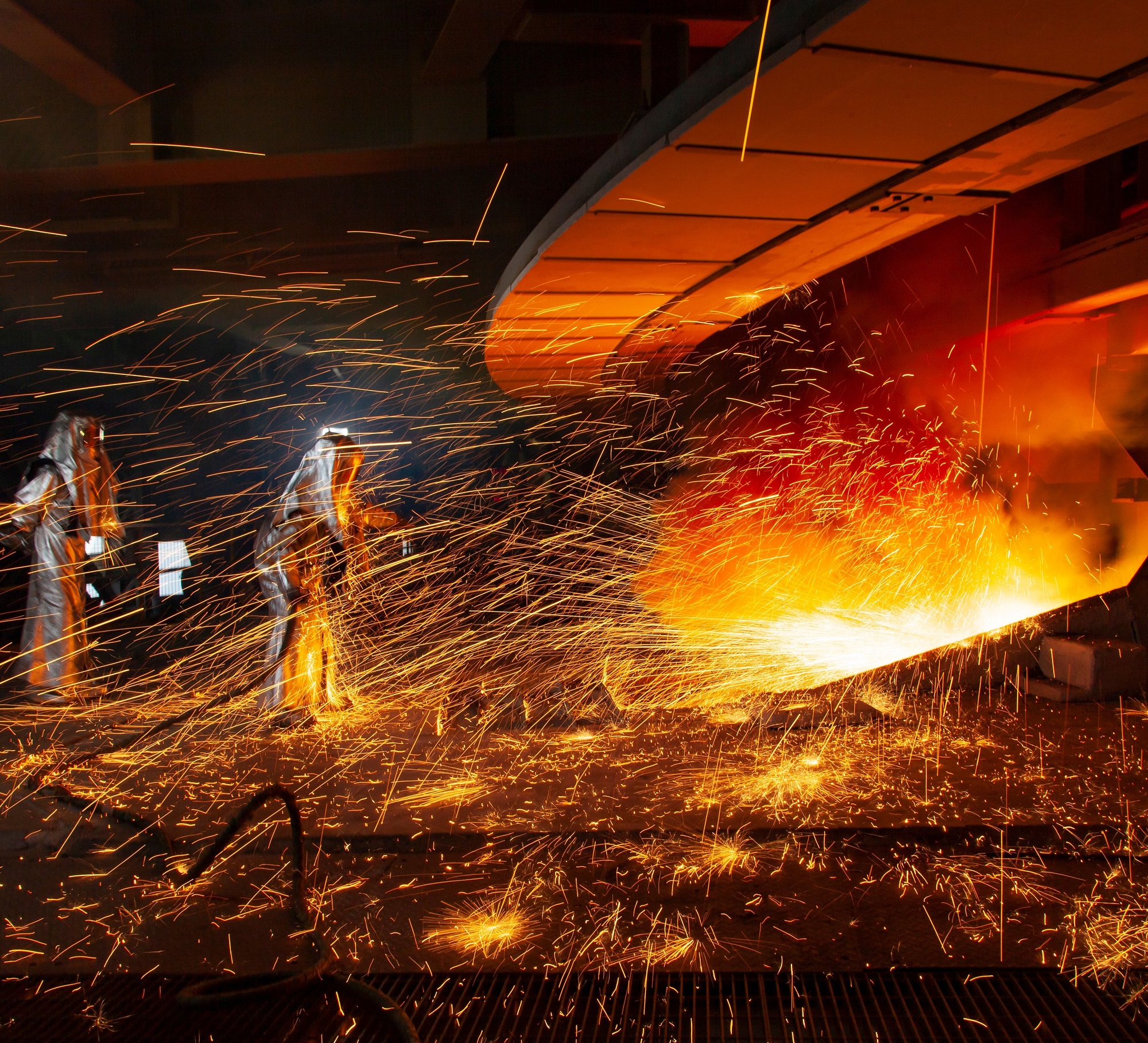 The Two Factory Workers Igniting A Furnace In An Industrial Factory.